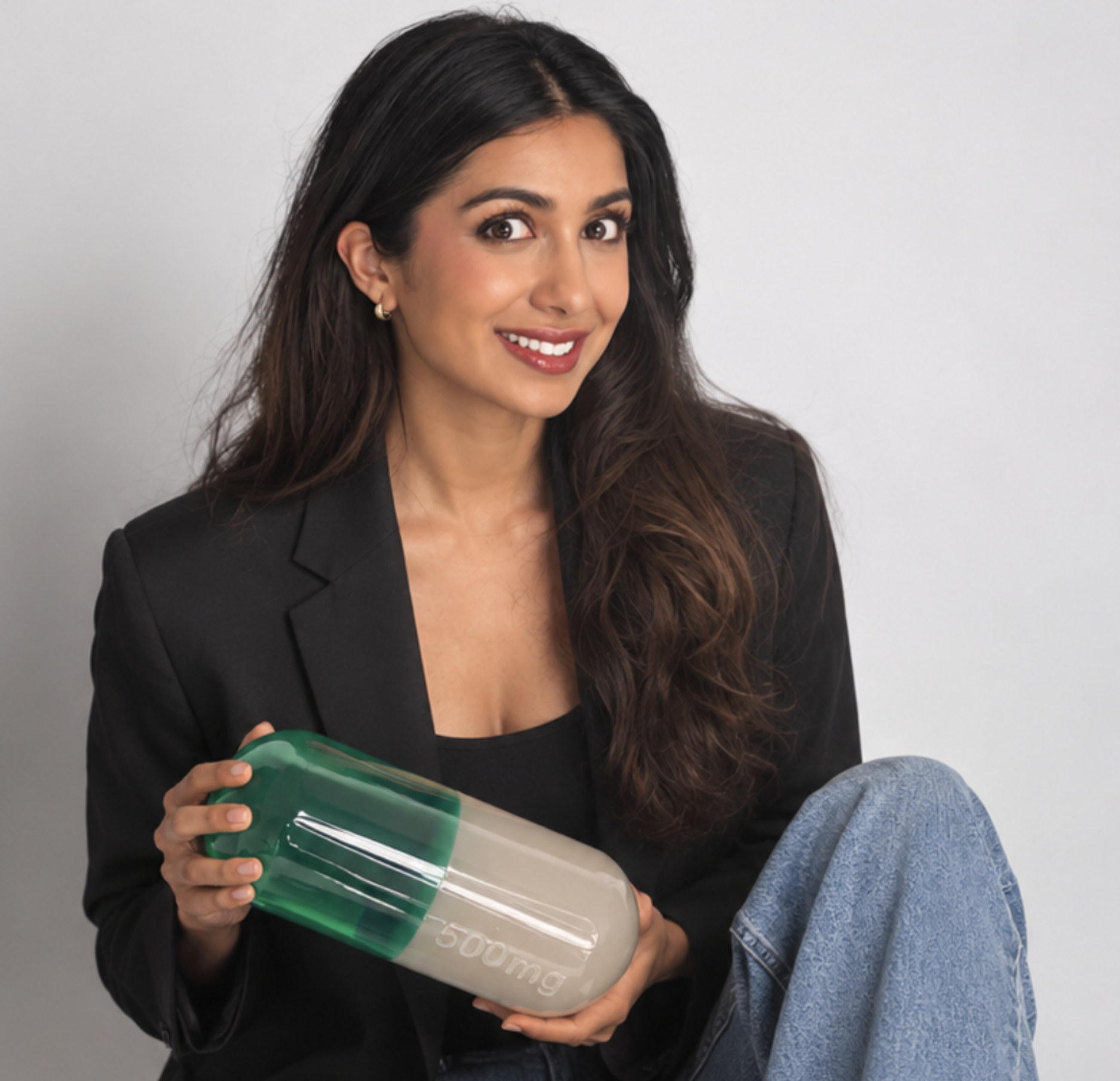 Deeya Kotecha holding a green and ivory capsule sculpture